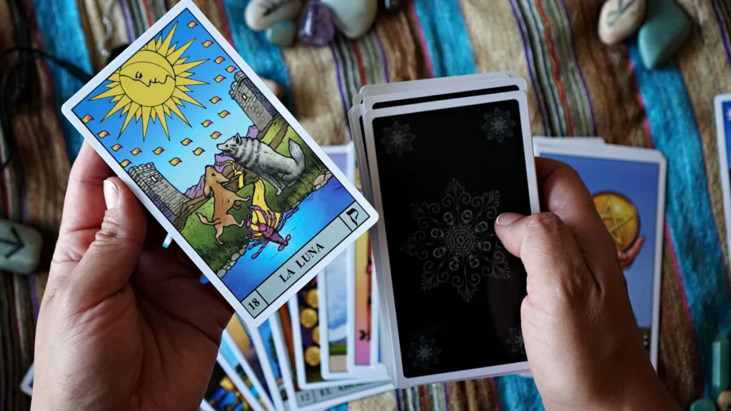tarot card beside a stacked deck, with a fanned spread in the background.